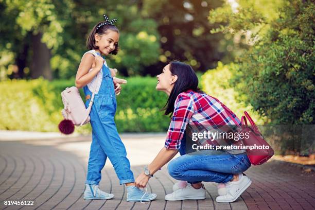 mother is tying shoelaces of her beloved daughter - tieing shoelace stock pictures, royalty-free photos & images