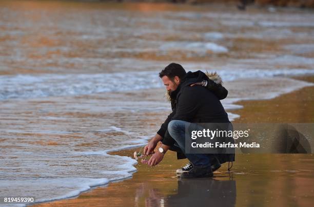 Jason Ruszczyk, the brother of Justine Damond, is seen placing a flower into the water during a vigil for his sister at Freshwater Beach on July 19,...