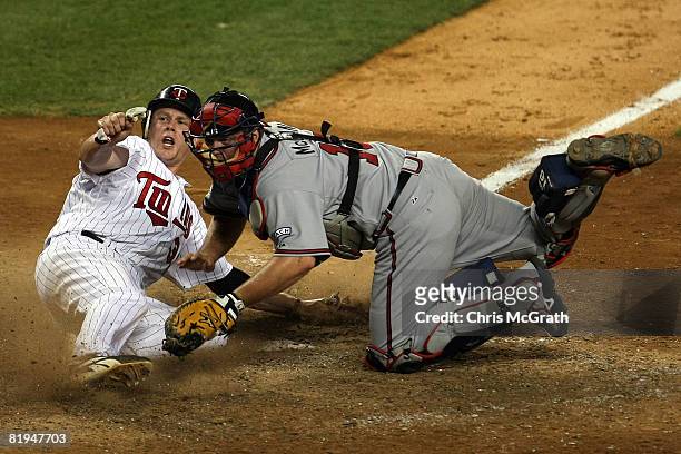American League All-Star Justin Morneau of the Minnesota Twins slides into home ahead of the tag of National League All-Star catcher Brian McCann of...