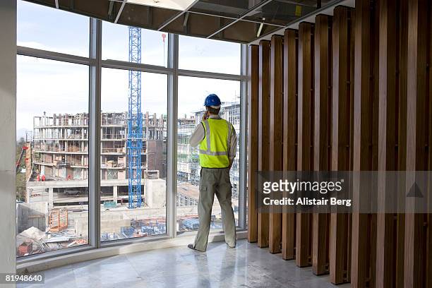 building worker using cell phone inside office development - construction worker office people stock pictures, royalty-free photos & images