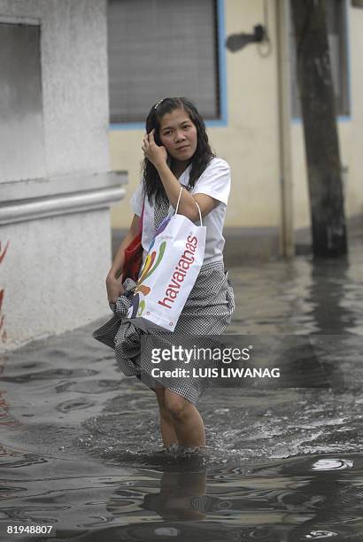 Pedestrian wades through a flooded street in Malabon, north of Manila on July 16, 2008. Monsoon rains from the tropical storm "Helen" brought strong...