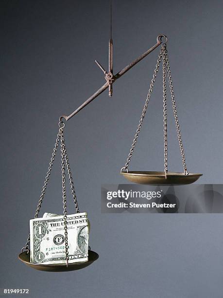 scale weighing the value of us currency - uneven stock pictures, royalty-free photos & images