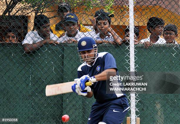 Indian cricketer Virender Sehwag hits a ball as Sri Lankan schoolchildren watch as during a practice session at the Sinhalease Sports Club Ground in...