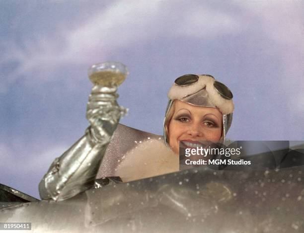 English model and actress Twiggy, as Polly Browne, raises a champagne glass in the cockpit of an aeroplane in a scene from the fim version of Sandy...