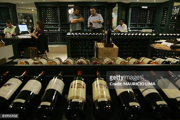 Client listens to details about a bottle of red wine from a shop assistant at an imported wines' shop, in Sao Paulo, Brazil, on July 16, 2008....