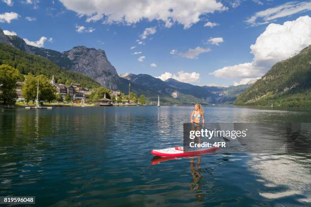 frau stand up paddling (sup) auf see grundlsee, österreich - region grundlsee stock-fotos und bilder