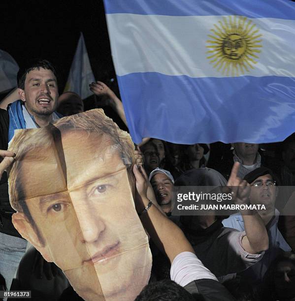 Farmers react holding a portrait of Argentina's Vice President Julio Cobos and the national flag while senators vote to reject a controversial...