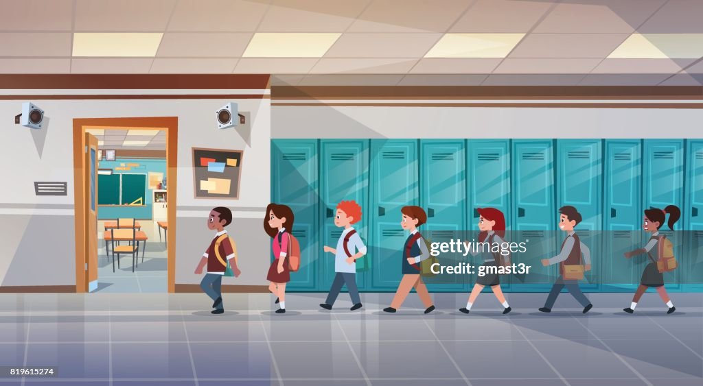 Group Of Pupils Walking In School Corridor To Class Room, Mix Race Schoolchildren