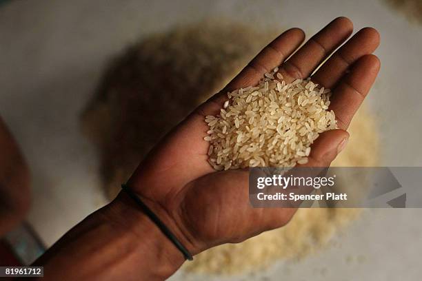 Man holds a handful of rice grains at a market on July 17, 2008 in Dhaka, Bangladesh. Bangladesh has recently closed nearly 2,000 rice mills because...