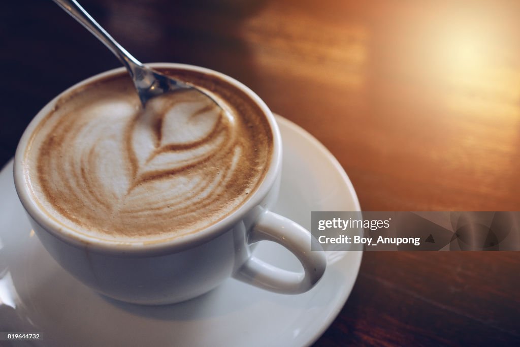 A cup of Latte coffee on the wooden table.