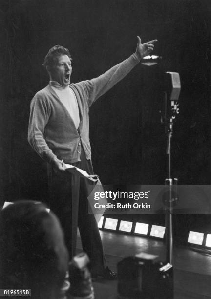 American comic actor Danny Kaye gestures expansively as he sings into a WNBC radio microphone, New York, late 1940s or early 1950s.