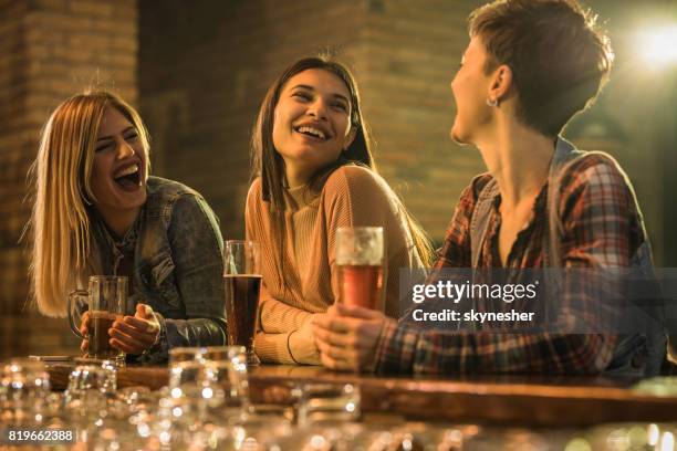 happy women having fun while drinking beer and talking at bar counter. - ladies night stock pictures, royalty-free photos & images