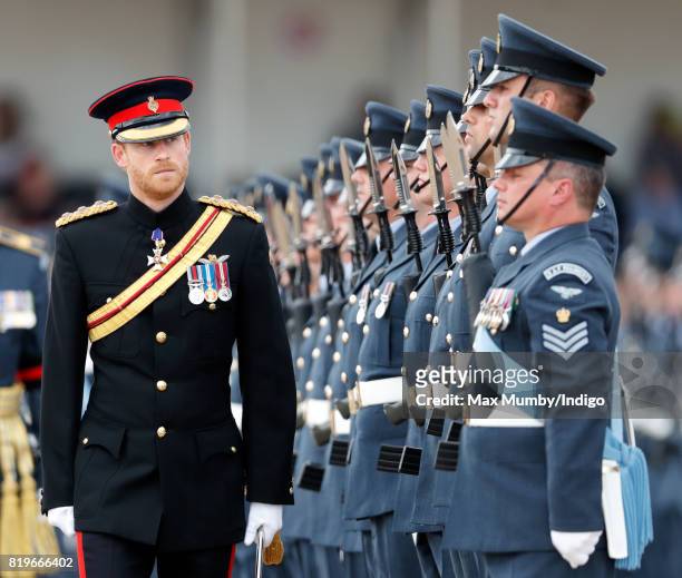 Prince Harry inspects a parade as he, on behalf of his grandmother Queen Elizabeth II, presents the RAF Regiment with a new Colour in their 75th...