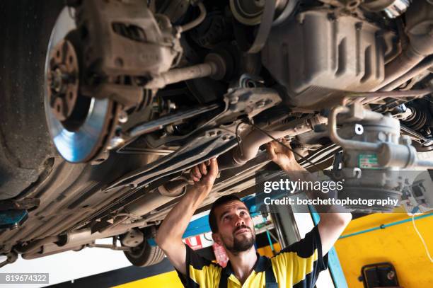 car mechanic at work repairing car chassis - car underside stock pictures, royalty-free photos & images