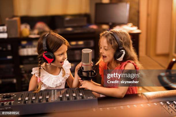 happy little girls broadcasting a radio show from the station. - kids singing stock pictures, royalty-free photos & images