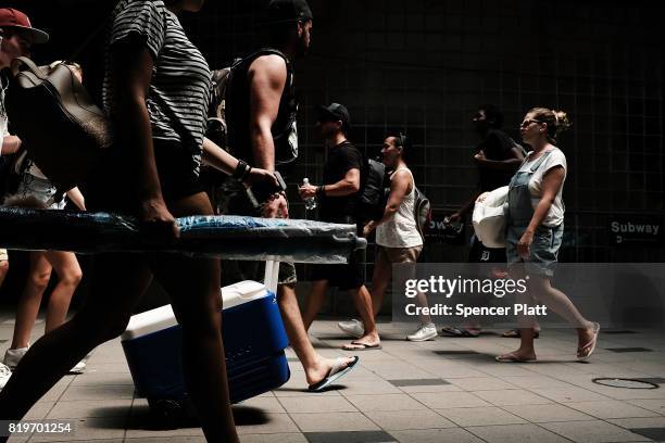 People walk on a summer day to the beach at Coney Island on July 20, 2017 in the Brooklyn borough of New York City. Throughout the region people...