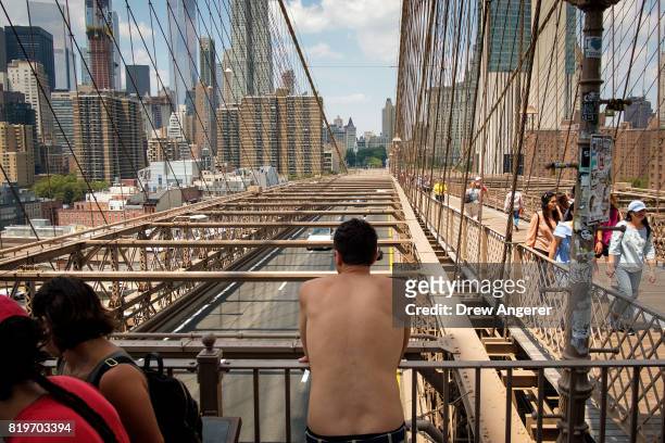 Shirtless man takes in the view on the Brooklyn Bridge, July 20, 2017 in New York City. Thursday is forecasted to be the hottest day of the year so...
