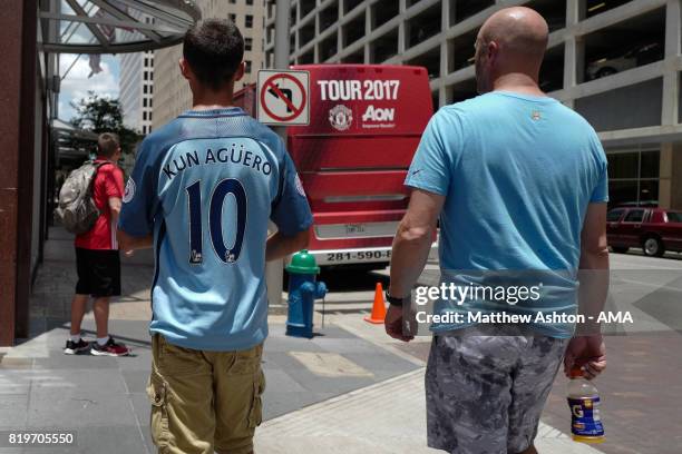 Fans of Manchester City walk in downtown Houston past the Manchester United team bus prior to the International Champions Cup 2017 match between...