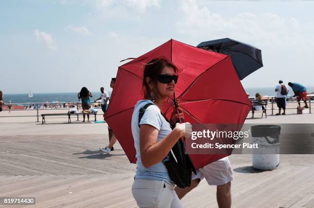 Woman tires to stay out of the sun on the boardwalk at Coney Island on July 20, 2017 in the Brooklyn borough of New York City. Throughout the region...