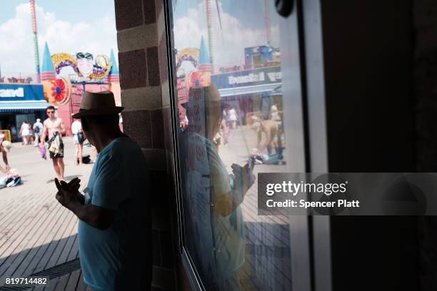 Man tries to stay out of the sun on the boardwalk at Coney Island on July 20, 2017 in the Brooklyn borough of New York City. Throughout the region...