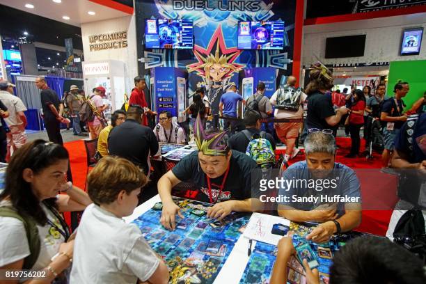 Visitors play Duel Links at their booth during Comic Con International on July 20, 2017 in San Diego, California. Comic Con International is North...