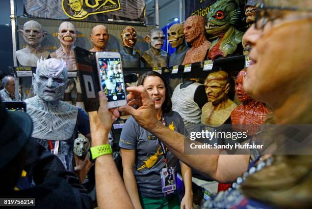 Carol Smith,L, tries on a rubber mask at the CFX Composite Effects booth at Comic Con International on July 20, 2017 in San Diego, California. Comic...