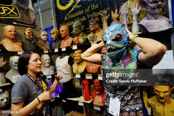 Carol Smith tries on a rubber mask at the CFX Composite Effects booth at Comic Con International on July 20, 2017 in San Diego, California. Comic Con...