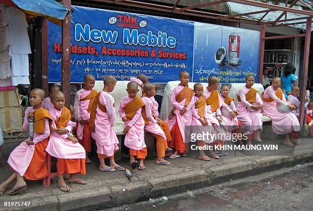 Young novice Buddhist nuns wait at a bus stop in downtown Yangon on July 17, 2008. Buddhists around the region have been marking the festival of...