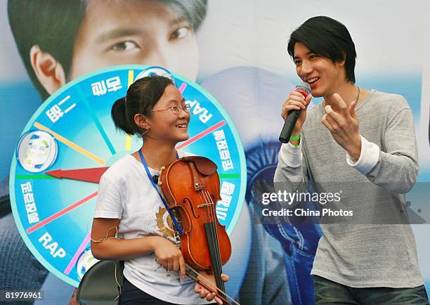 Musician Wang Leehom and a young fan perform during his "Against All Odds" roadshow on July 17, 2008 in Nanjing of Jiangsu Province, China.