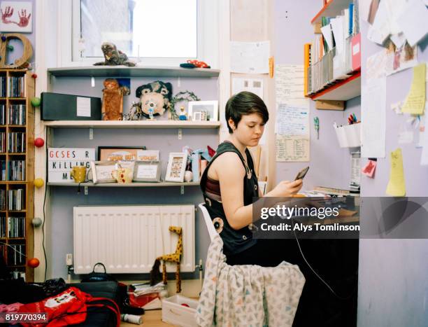 teenage girl sitting at desk in bedroom, using mobile phone - girl bedroom stock pictures, royalty-free photos & images