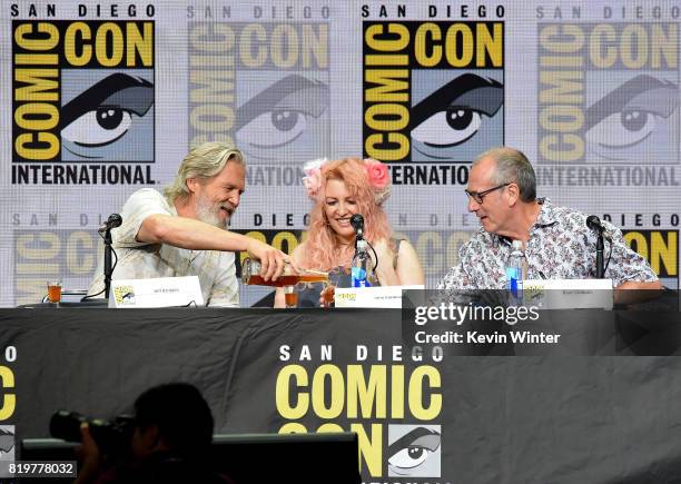 Actor Jeff Bridges pours shots for screenwriter Jane Goldman and writer/executive producer Dave Gibbons onstage at the 20th Century FOX panel during...