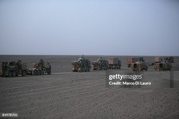 British Army trucks from the 13 Air Assault Support Regiment drive through the desert at sunrise after the overnight break during an operation to...