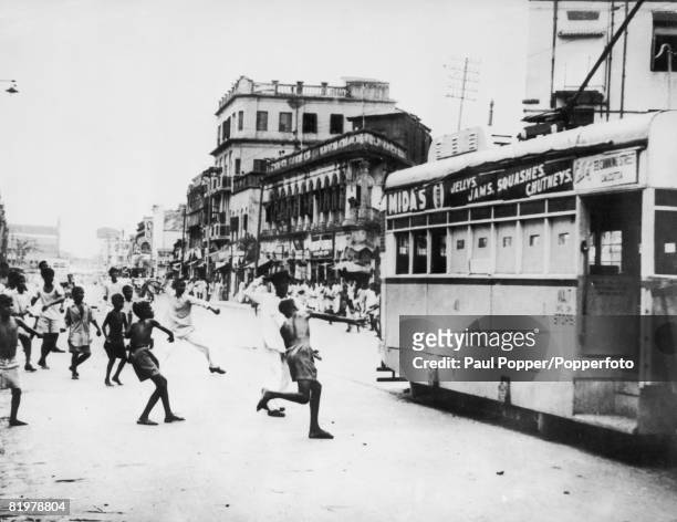 Men and boys join together to throw stones at a tram in Calcutta, 1st April 1947.