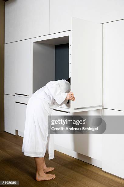 a man looking into an opened cabinet - bog stock-fotos und bilder