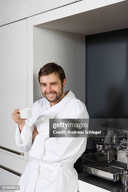 a smiling man in a bathrobe holding a coffee cup - espressomaschine stock-fotos und bilder