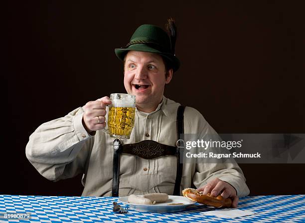 stereotypical german man holding a beer and a pretzel - estereotipo fotografías e imágenes de stock