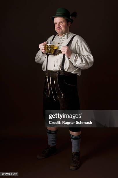 stereotypical german man in bavarian costume holding a beer - homme en contre plongée fait le pitre photos et images de collection