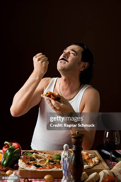 stereotypical italian man looking up and gesturing while eating pizza - stereotypical foto e immagini stock