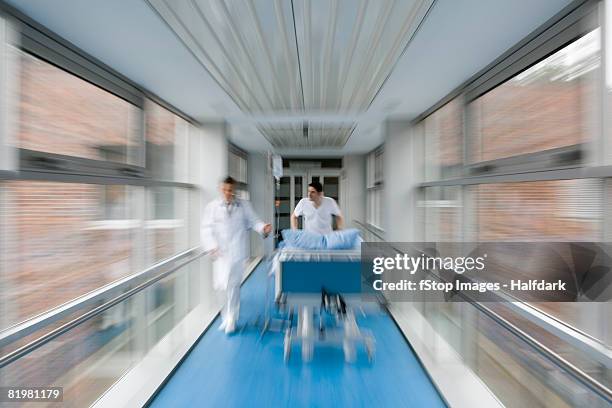 two healthcare workers pushing a hospital bed along a corridor - missgeschick stock-fotos und bilder