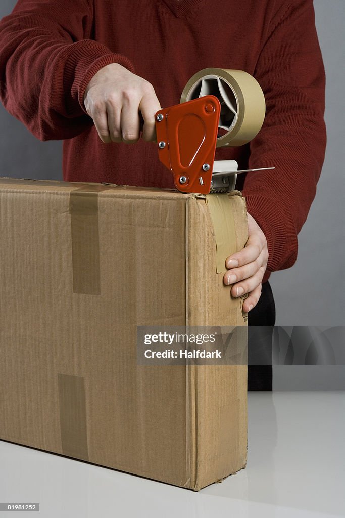 A man taping a cardboard box