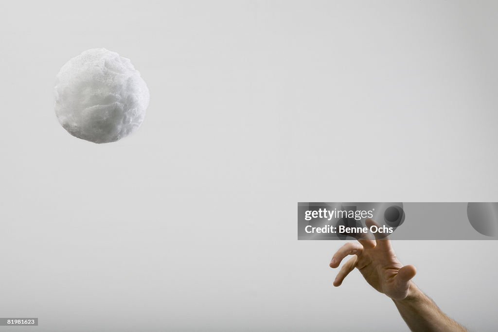 A human hand throwing a large cotton ball