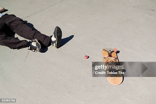 a skateboarder lying on the floor next to a broken skateboard - broken skateboard stockfoto's en -beelden