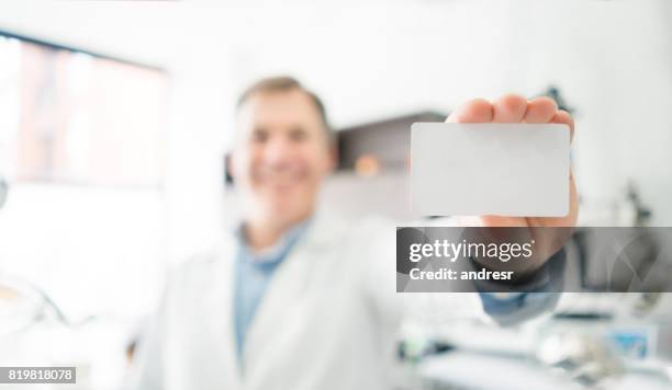 retrato de un dentista feliz sosteniendo una tarjeta de visita - tarjeta de lealtad fotografías e imágenes de stock