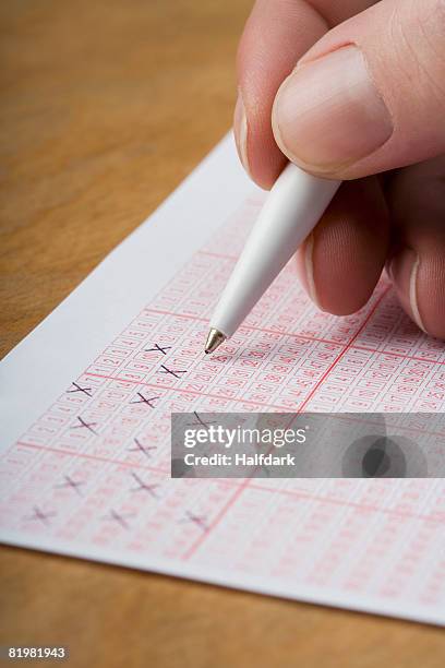 a hand marking a lottery ticket - lotterie stock-fotos und bilder