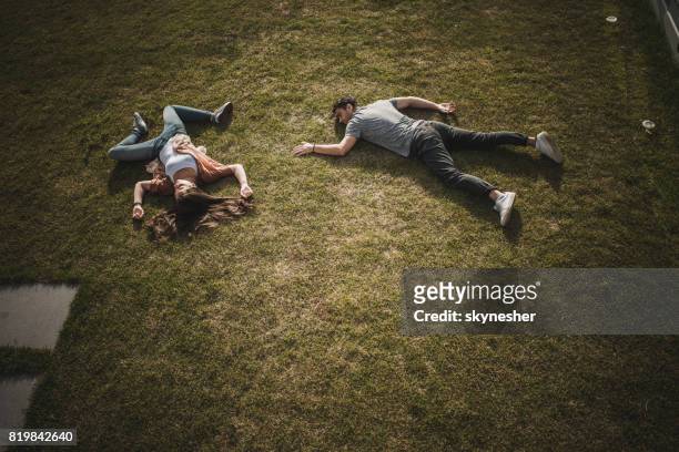 above view of unconscious couple lying on the grass. - coma stock pictures, royalty-free photos & images