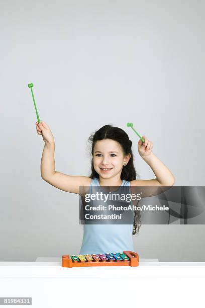 little girl playing xylophone, arms raised, smiling - xilofone imagens e fotografias de stock