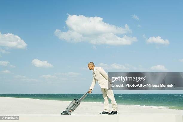 man in suit using vacuum cleaner on beach, full length - futility stock pictures, royalty-free photos & images