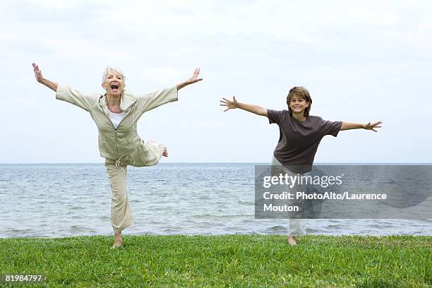 grandmother and grandson standing on one leg, arms outstretched, both smiling at camera - open day 7 stockfoto's en -beelden