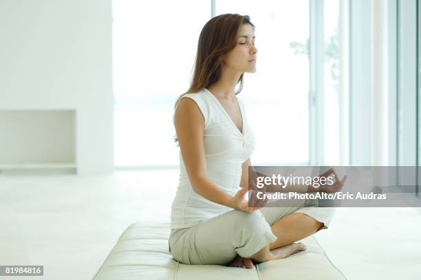 young woman sitting in lotus position, eyes closed, side view - hand on knee stock pictures, royalty-free photos & images