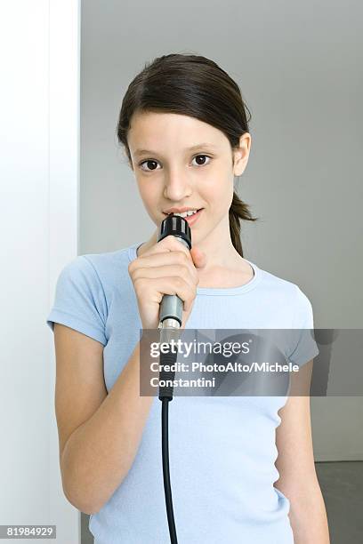 preteen girl singing into microphone, smiling at camera - holding microphone stock pictures, royalty-free photos & images